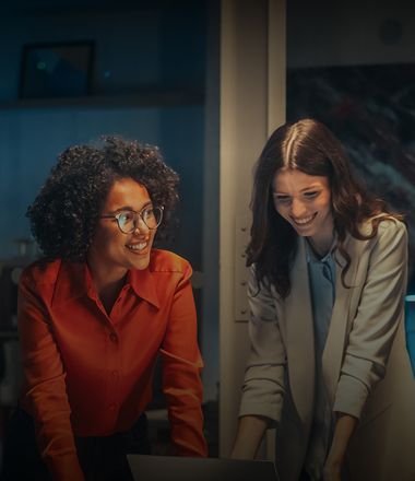 Two women are happily looking at the screen of the laptop