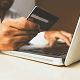 Person holding a credit card while typing on a laptop for online payment